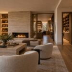 Editorial cutaway-style view of a contemporary luxury residence showing a calm living space beside an organized service core containing a back kitchen, pantry, stair, storage, utility rooms, and vertical service zones.