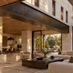 Contemporary great room beneath a substantial exposed transfer girder, opening toward a sheltered garden terrace.
