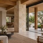 Contemporary living room with limestone support column, oak beam connections, sheltered terrace pier, and courtyard garden.