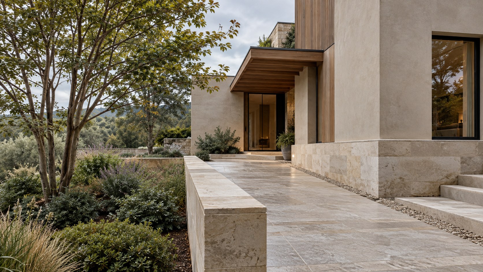 Contemporary limestone residence on a modest raised stone plinth with a sheltered entry, graded path, and planted courtyard.