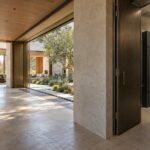 Contemporary stone and timber residence with a discreet, accessible electrical service room opening onto a secondary gallery.